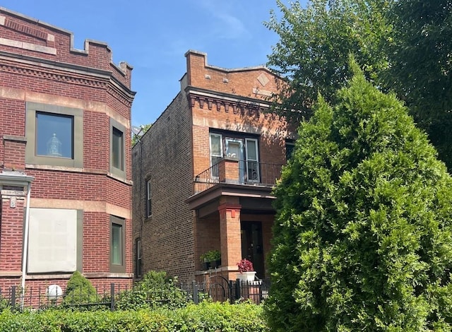 view of front facade with brick siding and a balcony