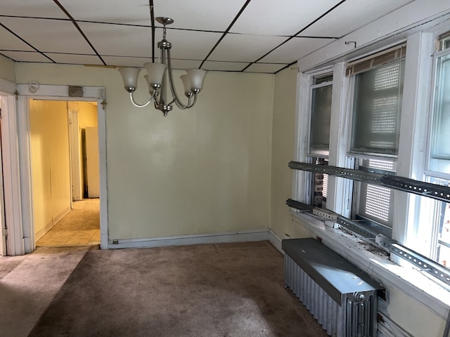 spare room with a paneled ceiling, an inviting chandelier, and light carpet