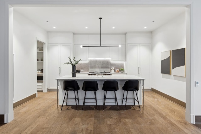 kitchen with light countertops, a center island, white cabinetry, and light wood-style floors