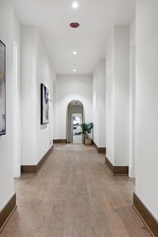 hall with baseboards, arched walkways, wood finished floors, and recessed lighting