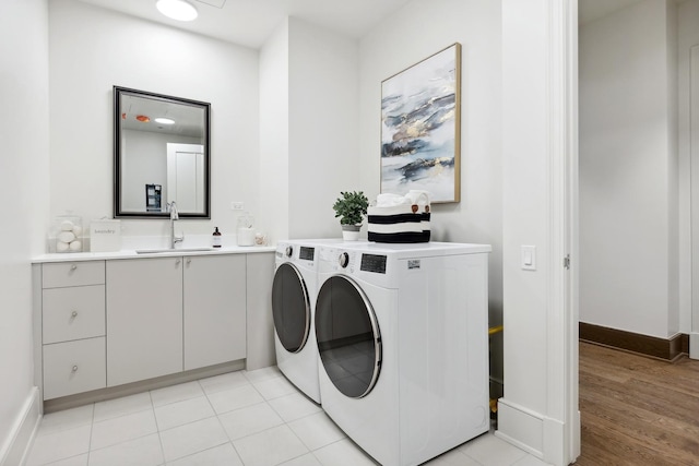 laundry area featuring cabinet space, baseboards, washer and dryer, and a sink