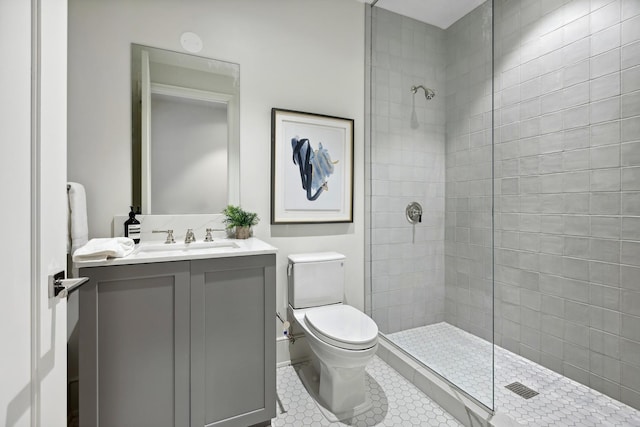 bathroom featuring tile patterned flooring, tiled shower, vanity, and toilet