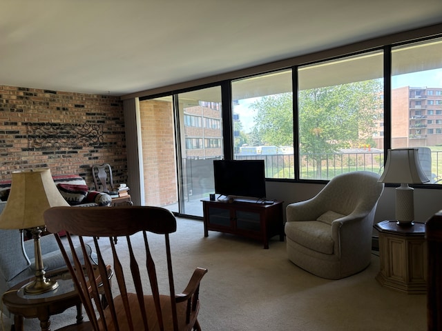 carpeted living room with a healthy amount of sunlight and brick wall