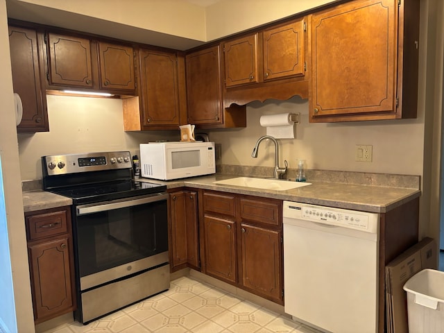 kitchen featuring sink, white appliances, and light tile patterned floors