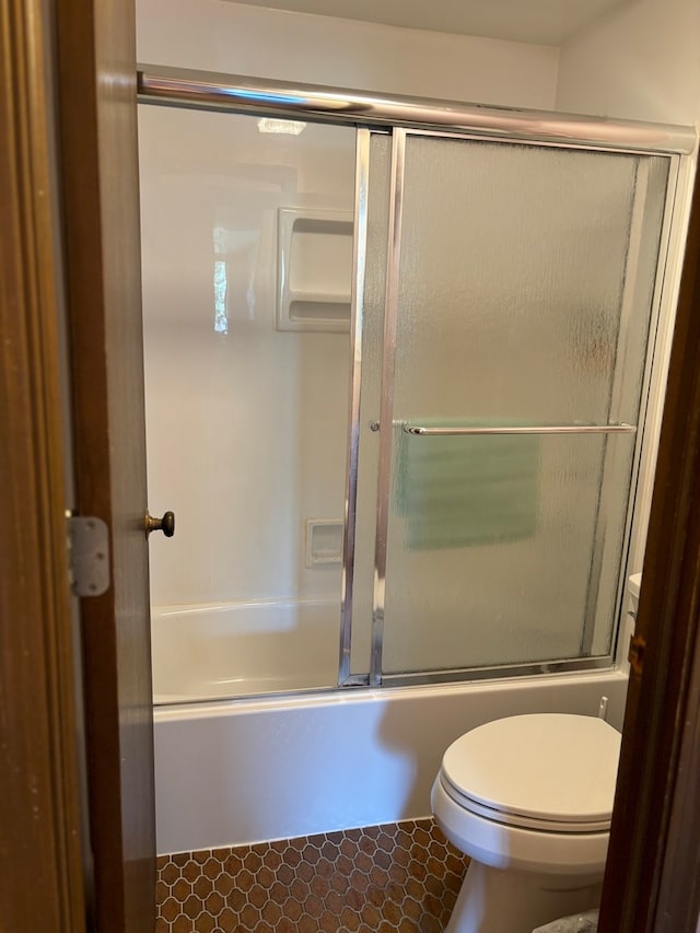 bathroom featuring enclosed tub / shower combo, tile patterned flooring, and toilet