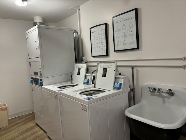 clothes washing area featuring stacked washer and dryer, washing machine and clothes dryer, sink, and wood-type flooring