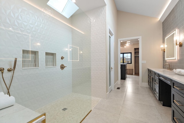 bathroom with a skylight, baseboards, tile patterned flooring, vanity, and a walk in shower