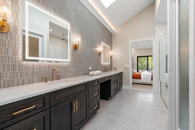 full bath featuring lofted ceiling, double vanity, a sink, and tile walls