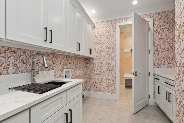 clothes washing area with hookup for a washing machine, sink, and cabinets