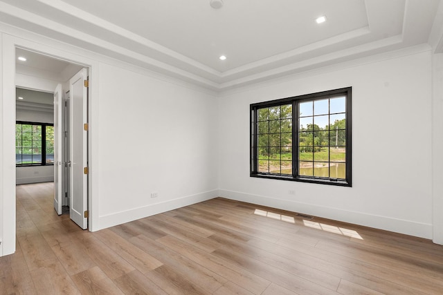 unfurnished room featuring light wood-type flooring, a raised ceiling, and baseboards