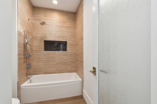 bathroom with tub / shower combination, toilet, and wood finished floors