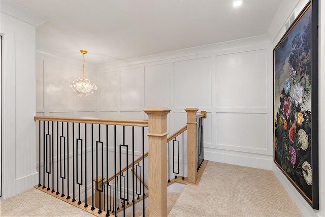 hallway with a notable chandelier, carpet floors, an upstairs landing, and a decorative wall