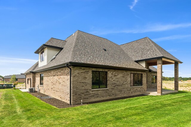 back of property with central air condition unit, a yard, and a patio