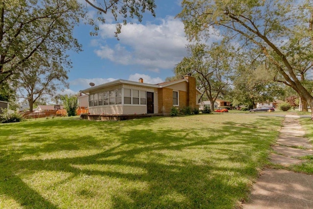 exterior space featuring a lawn, a chimney, and a sunroom