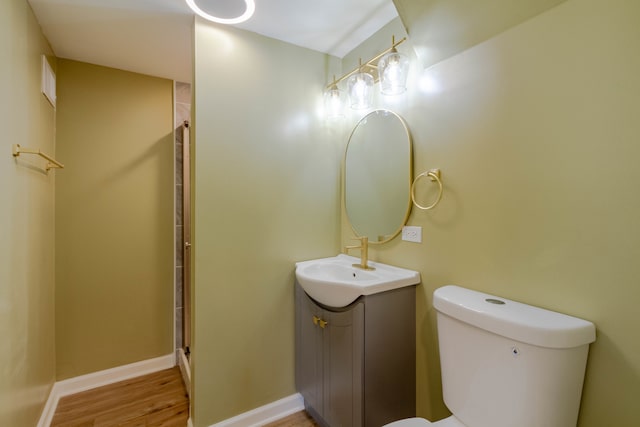 bathroom with hardwood / wood-style flooring, a shower with door, vanity, and toilet