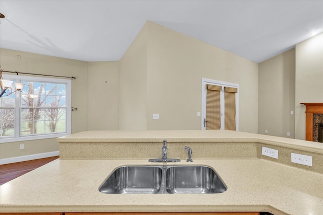 kitchen featuring hardwood / wood-style floors, a notable chandelier, a premium fireplace, and sink