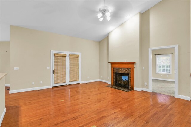 unfurnished living room with ceiling fan, light wood-type flooring, a fireplace, and high vaulted ceiling