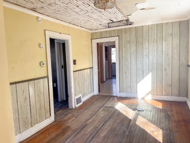 unfurnished room featuring hardwood / wood-style floors and wood walls