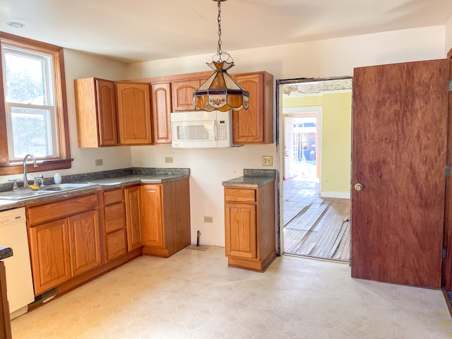 kitchen with light tile patterned floors, sink, white appliances, and decorative light fixtures