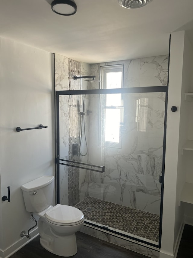 bathroom featuring hardwood / wood-style flooring, a shower with shower door, and toilet