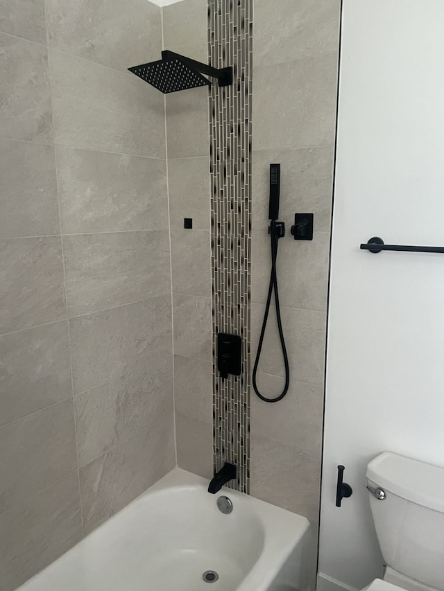 bathroom with tiled shower / bath combo and toilet