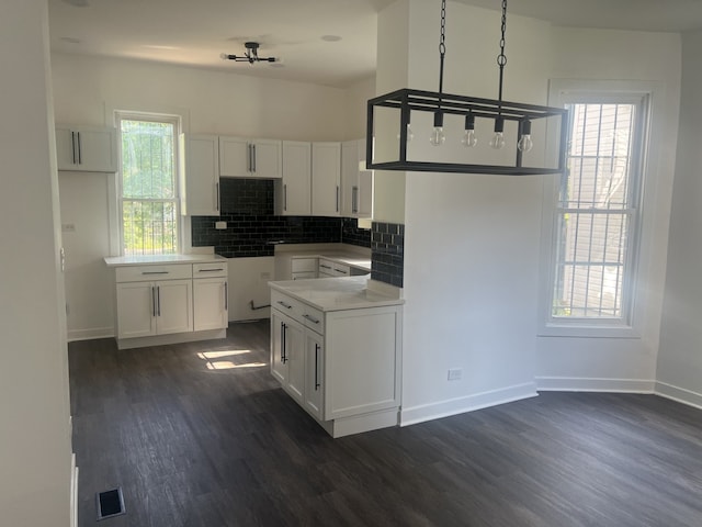 kitchen with dark hardwood / wood-style floors, a notable chandelier, white cabinets, decorative backsplash, and decorative light fixtures