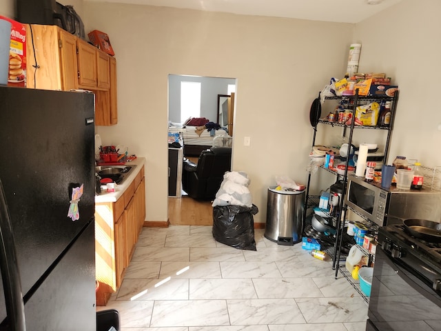 kitchen with light hardwood / wood-style floors and black fridge