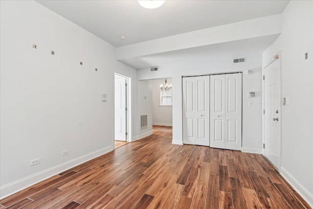 unfurnished bedroom featuring a closet, a chandelier, and dark wood-type flooring