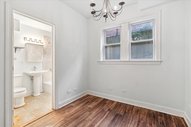 unfurnished bedroom with a notable chandelier, hardwood / wood-style floors, and ensuite bathroom