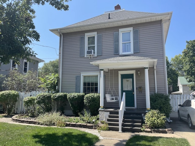 view of front of home with a shingled roof, a chimney, and fence