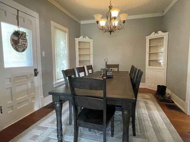 dining room featuring dark wood-type flooring, ornamental molding, and a chandelier