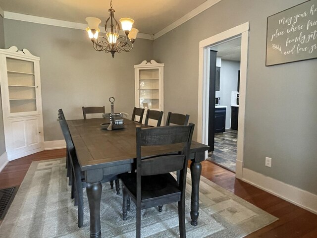 dining space with a notable chandelier, dark wood-type flooring, and ornamental molding