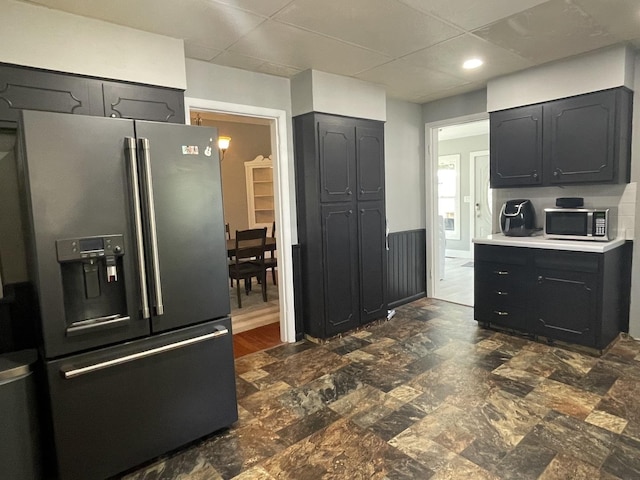 kitchen featuring appliances with stainless steel finishes, light countertops, dark cabinets, and wainscoting