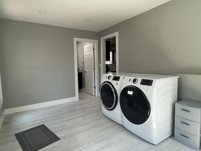 laundry area with laundry area, light wood-type flooring, washing machine and dryer, and baseboards