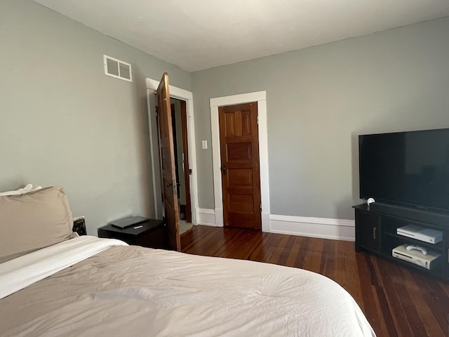 bedroom with dark wood-style flooring, visible vents, and baseboards