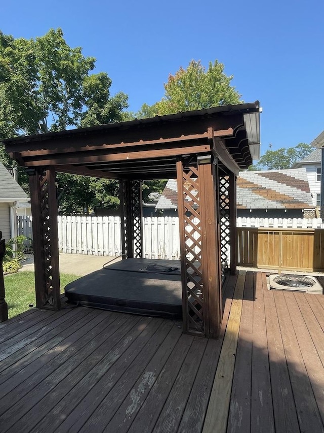 deck featuring a covered hot tub and fence