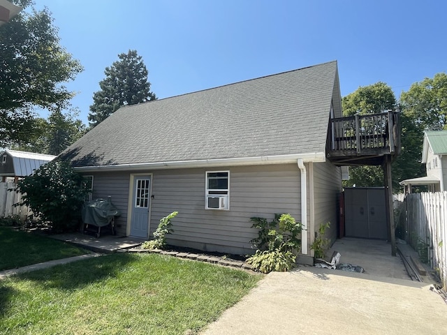 exterior space featuring roof with shingles, a lawn, and fence