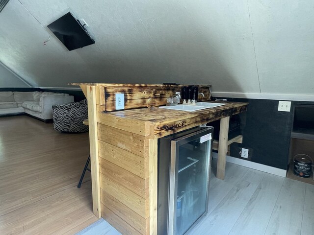 interior space featuring sink, lofted ceiling, hardwood / wood-style floors, and beverage cooler