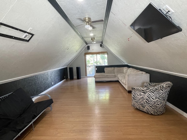 additional living space with baseboards, ceiling fan, wood finished floors, vaulted ceiling, and a textured ceiling