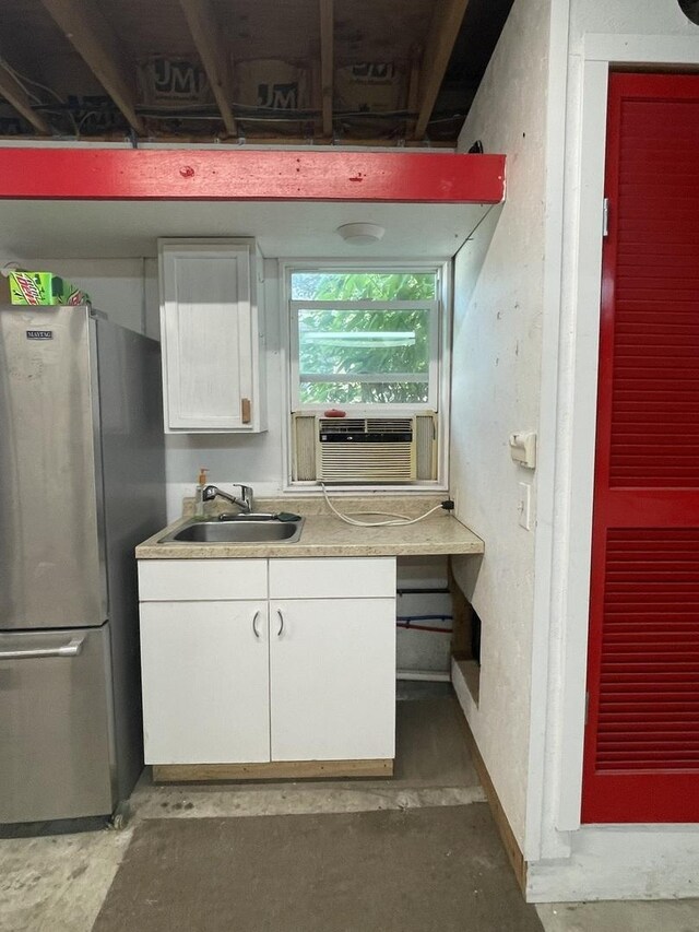 kitchen featuring sink, concrete floors, white cabinetry, and stainless steel refrigerator