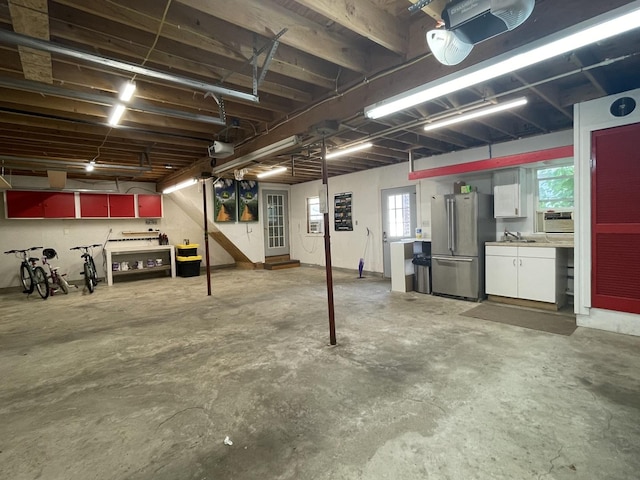 garage featuring a sink, freestanding refrigerator, and a garage door opener