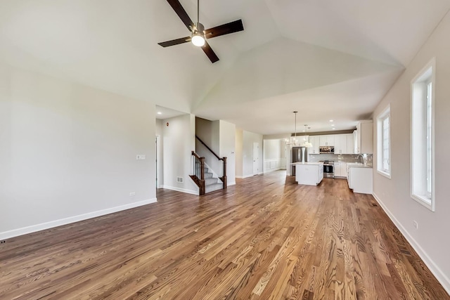 unfurnished living room featuring ceiling fan, lofted ceiling, hardwood / wood-style floors, and sink