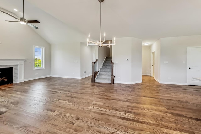 unfurnished living room featuring high vaulted ceiling, ceiling fan with notable chandelier, and hardwood / wood-style flooring