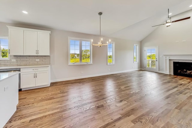 kitchen with backsplash, light hardwood / wood-style flooring, decorative light fixtures, white cabinetry, and ceiling fan with notable chandelier