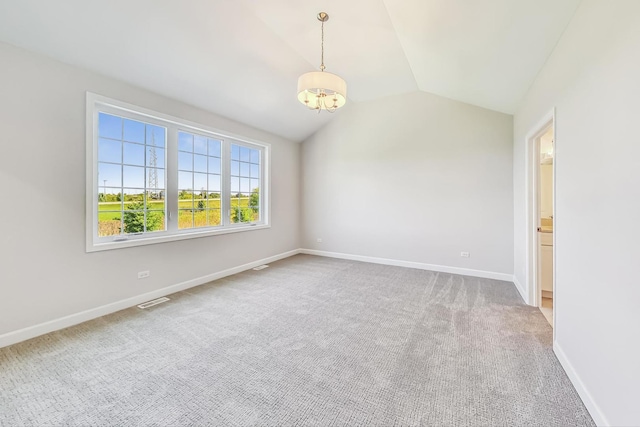 carpeted spare room featuring a notable chandelier and lofted ceiling