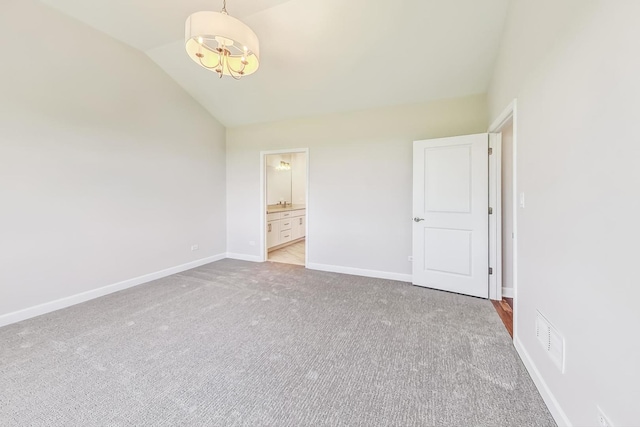 unfurnished bedroom with lofted ceiling, light colored carpet, and ensuite bath