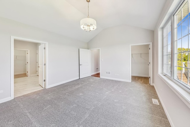 unfurnished room featuring light colored carpet, vaulted ceiling, and an inviting chandelier