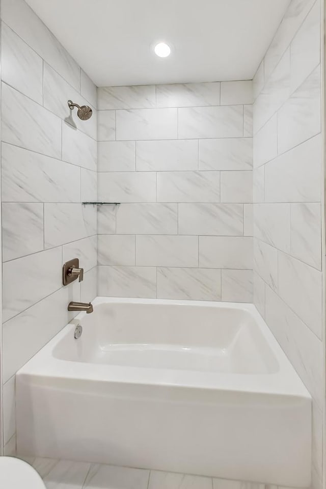 bathroom featuring toilet, tiled shower / bath, and tile patterned floors