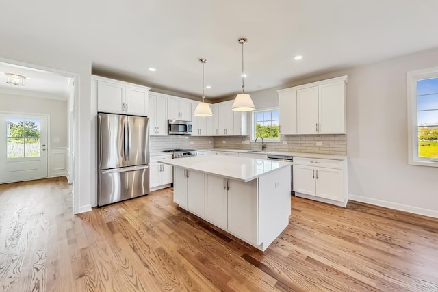 kitchen featuring a wealth of natural light, stainless steel appliances, white cabinetry, and light wood-type flooring