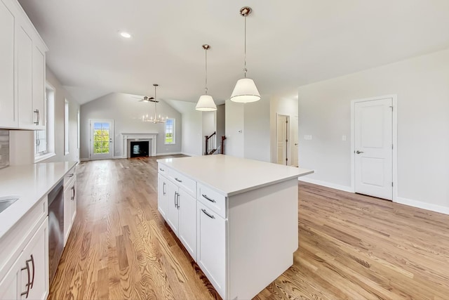 kitchen with light hardwood / wood-style flooring, white cabinetry, a center island, vaulted ceiling, and hanging light fixtures